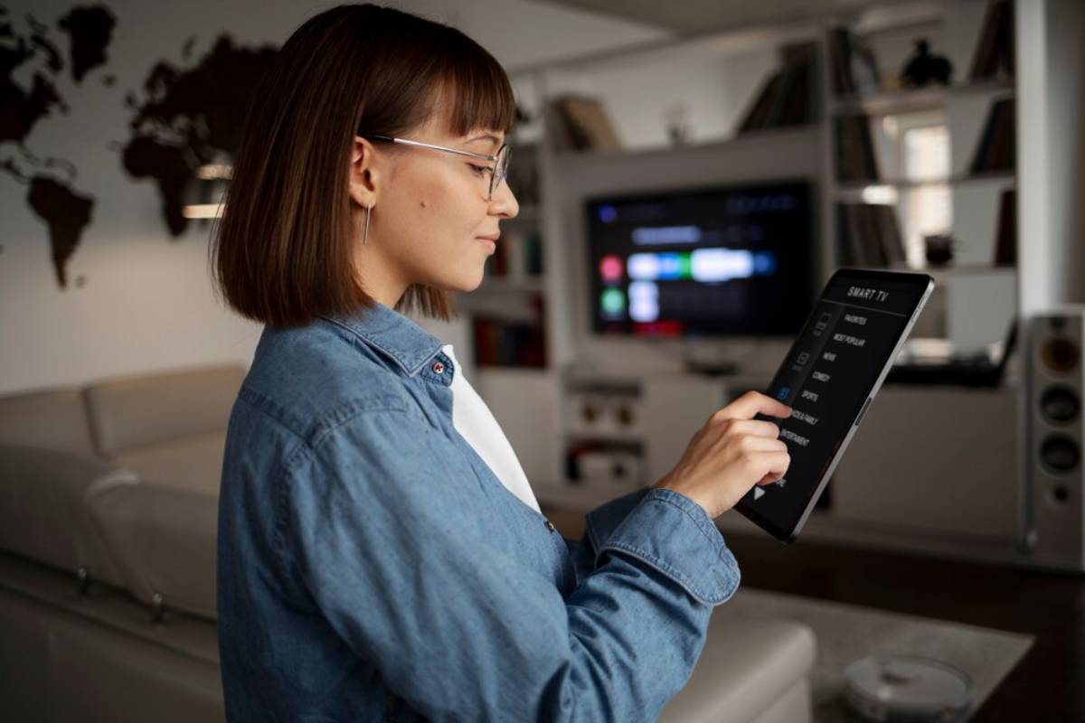 Woman in glasses using a smart home control tablet in a modern living room.