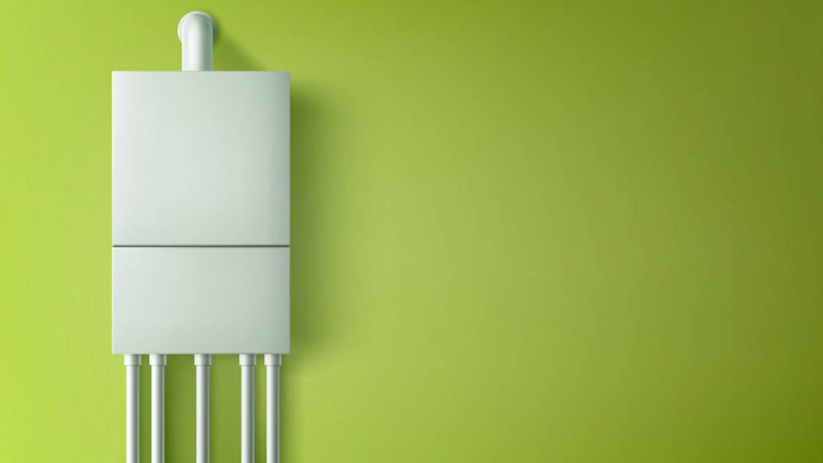 A white wall-mounted leak sensor device set against a vibrant green wall, with multiple pipes extending downward.